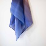 Hand-painted silk headscarf in vertical gradient shades of blue, purple, and orange, displayed against a white background