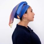 Hand-painted silk headscarf in vertical gradient shades of blue, purple, and orange, displayed against a white background
