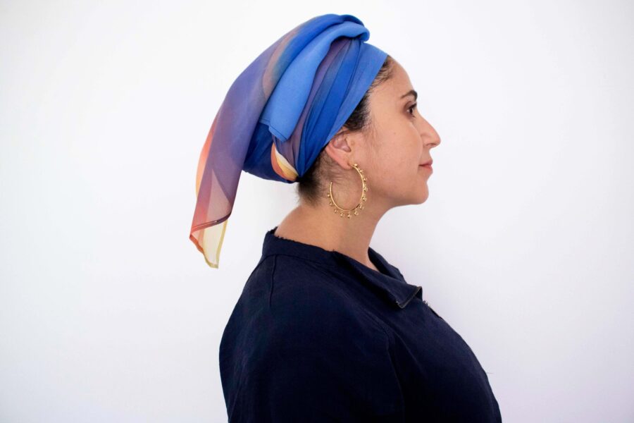 Hand-painted silk headscarf in vertical gradient shades of blue, purple, and orange, displayed against a white background